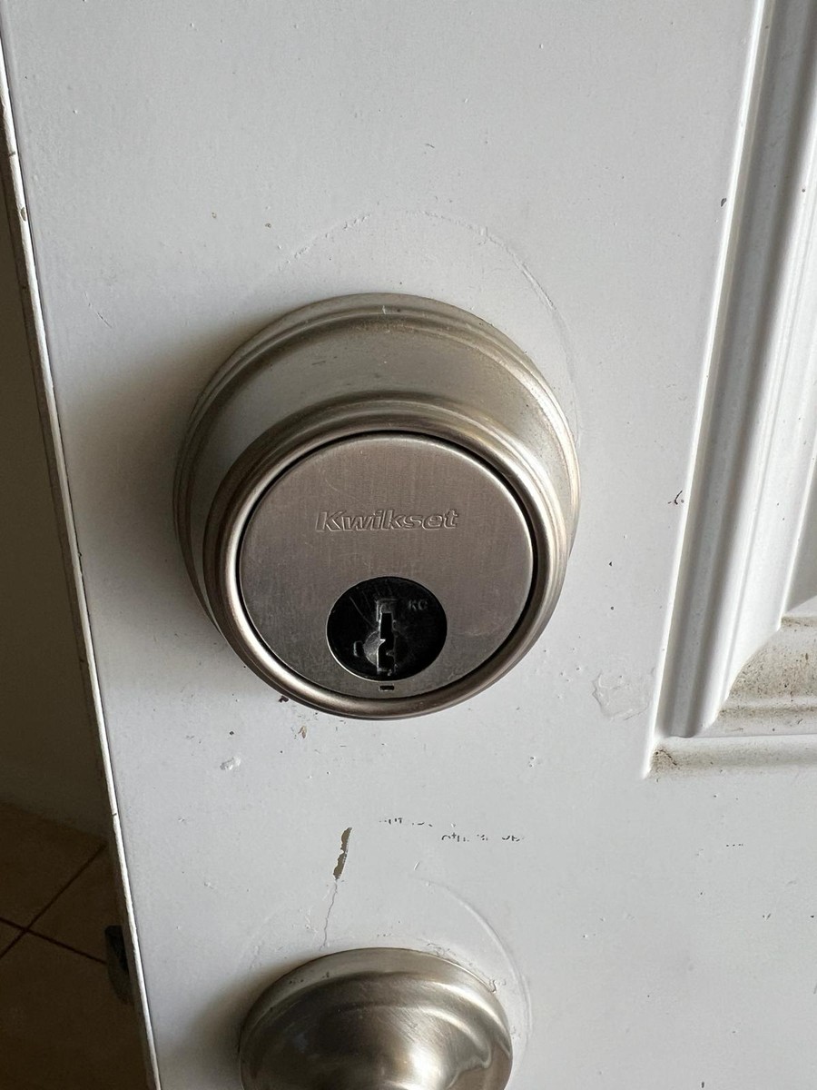 Round Kwikset deadbolt installed on a white entry door