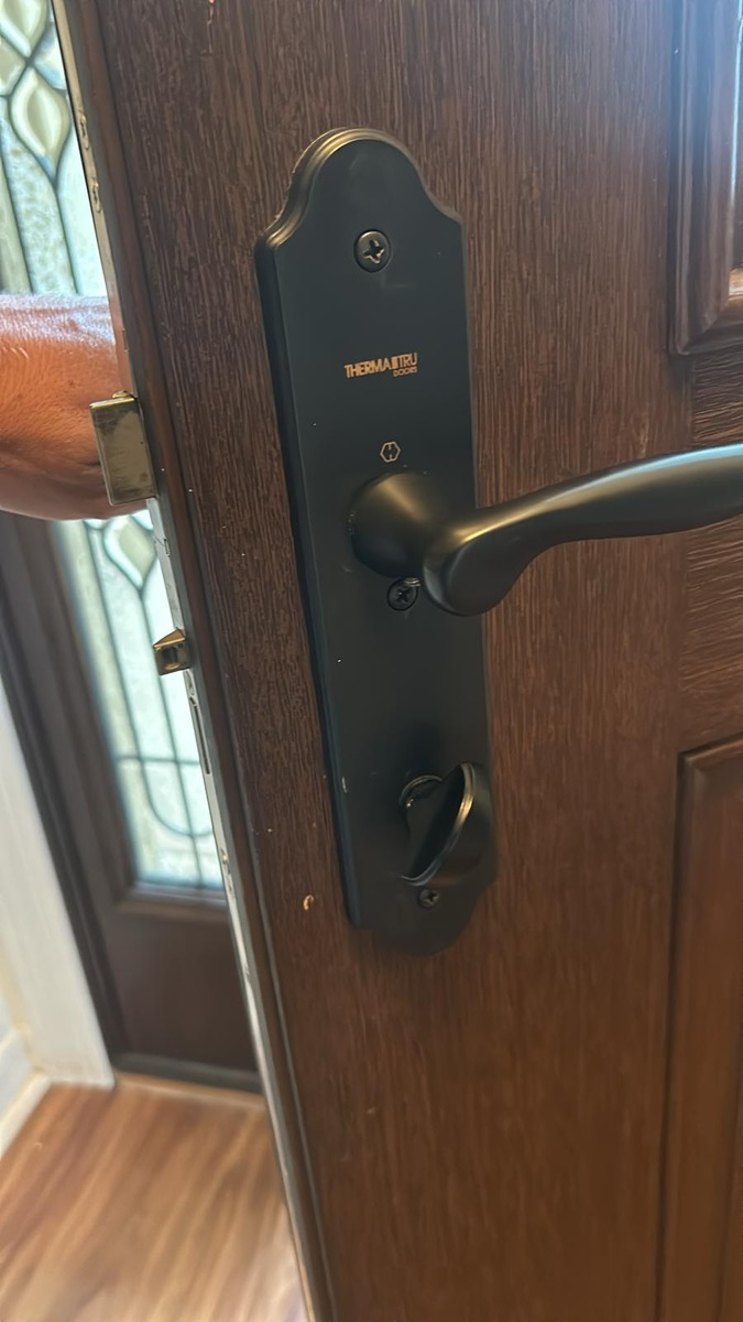 Matte black handleset installed on a wood-grain front door